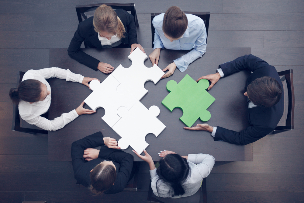 group of business people assembling puzzle, partnering concept